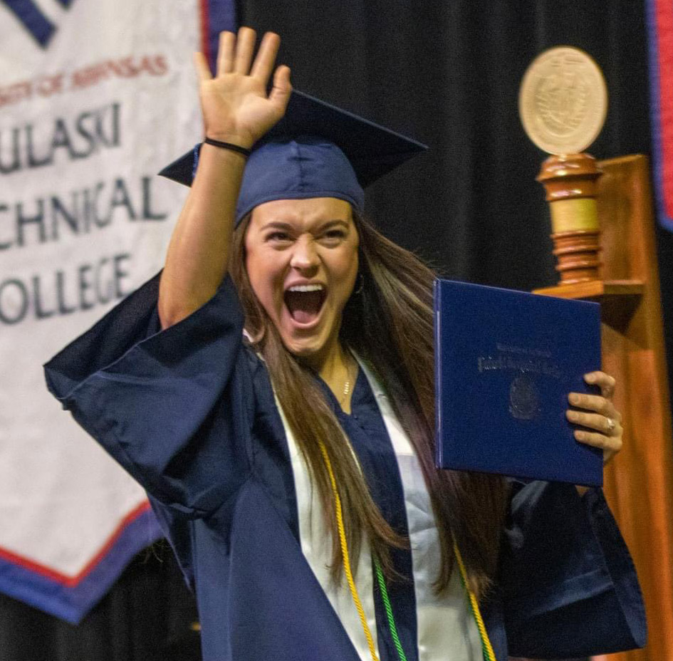 UA-PTC graduate on stage smiling and waiving at the crowd